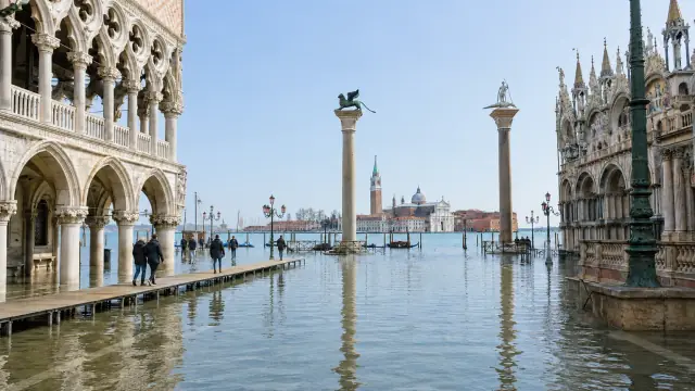Reconstruction of the Piazzetta in Venice under acqua alta, the Doge's Palace arcade and the two columns standing in still floodwater with figures on raised walkways.